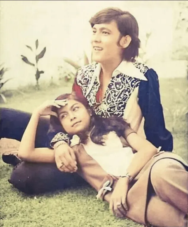 Retro-toned photo of a couple reclining together on grass, one resting against the other, in vintage clothing.