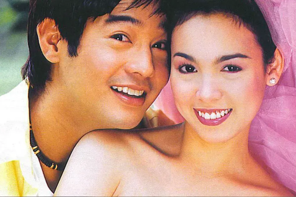 Vintage photo of a smiling young man and woman posed cheek to cheek, in 1990s styling.