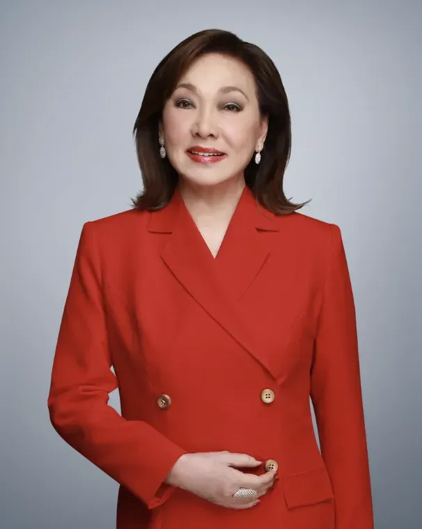 Studio portrait of a woman in a red blazer against a light background.
