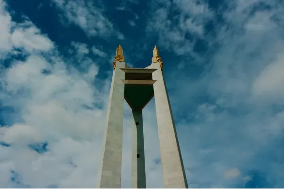 Photo looking up at a tall monument obelisk against a blue sky with scattered clouds.